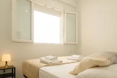 a white bedroom with a window and towels on a bed at Spacious Penthouse with Private Terrace in Valencia