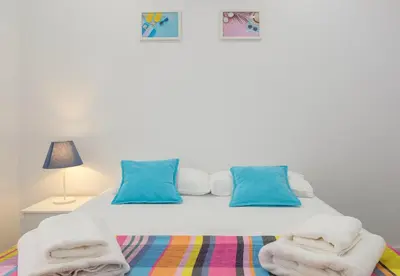 a white bed with blue pillows and towels on it at Spacious & Clean Apartment in Quiet Area in Valencia