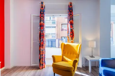 a yellow chair in a room with a window at Spacious Clean & Colorful Apt Quiet Zone in Valencia