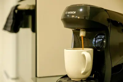 a coffee machine pouring coffee into a white cup at Modern Penthouse with Private Terrace in Valencia