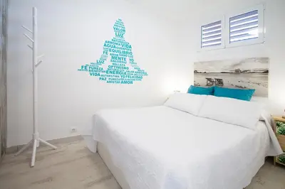 a bedroom with a white bed and a wall with words on it at PRIMERISIMA LINEA DE PLAYA - CULLERA BAHIA DE LOS NARANJOS I in Cullera