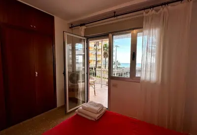 a bedroom with a red bed and a sliding glass door at Large Apartment with Sea Views in Sueca