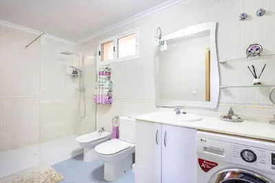 a white bathroom with a toilet and a sink at Balcón del Mar in Canet de Berenguer
