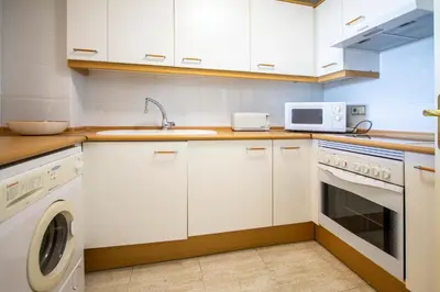 a kitchen with white cabinets and a washer and dryer at ESPACIO 2 Primera LINEA DE PLAYA in Cullera