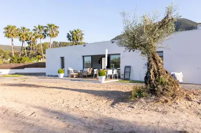 a white house on the beach with palm trees at Casa Rural Espadan Suites in Artana