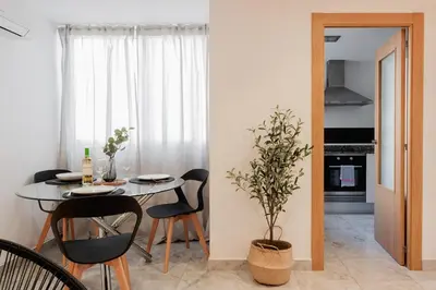 a dining room with a table and chairs and a plant at Apartamentos FV Flats Valencia - Mestalla 9 in Valencia