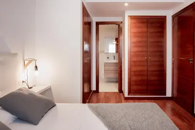 a bedroom with a white bed and a wooden closet at Apartamentos FV Flats Valencia - San Felipe Neri in Valencia