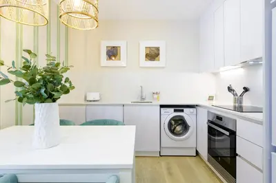 a white kitchen with a washing machine and a vase with a plant at MD Reina Cabañal Beach in Valencia