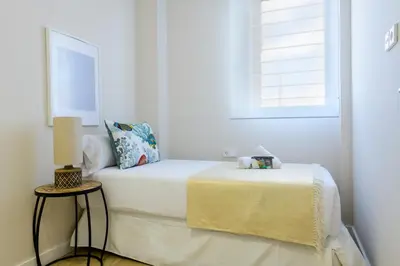 a white bedroom with a bed and a window at MD Reina Cabañal Beach in Valencia