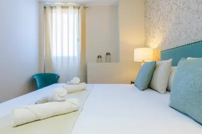 a bedroom with a large white bed with towels on it at MD Reina Cabañal Beach in Valencia