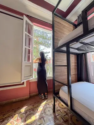 a woman looking out a window in a room with bunk beds at The Venue Hostel Boutique in Valencia