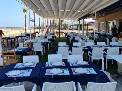 a group of tables and chairs with blue tables and white plates at 3Apto con piscina en la playa cerca de VLC con AC in Puzol