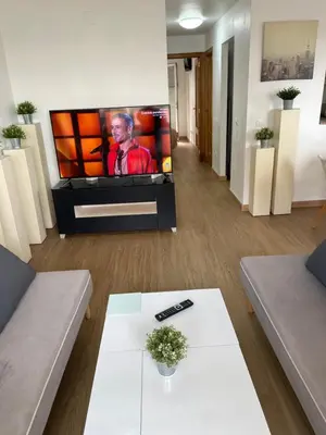 a living room with a flat screen tv and a table at PLAYA ALMARDA CORINTO, PISCINA, WIFI,2 TERRAZAS, BARBACOA,TRANQUILo in Sagunto