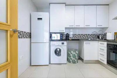 a kitchen with white appliances and a washer and dryer at Apart. Port Arenal con terraza y piscina in Burriana