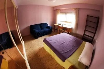 a bedroom with a bed and a blue couch at bigger flat for holiday near beach ideal for familie with climatisacion in Valencia