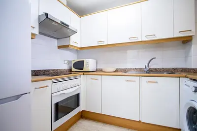 a kitchen with white cabinets and a sink and a microwave at 13 ESPACIO SOBRE MAR in Cullera