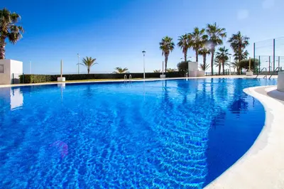 a large swimming pool with blue water and palm trees at 13 ESPACIO SOBRE MAR in Cullera