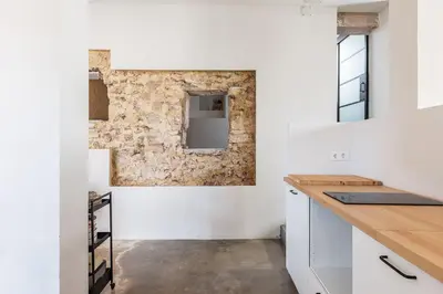 a kitchen with white cabinets and a stone wall at La Casa Baja in Sagunto