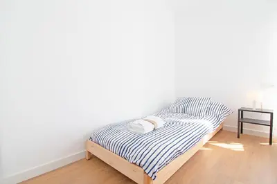 a bed in a room with a white wall at Global Vacacional, Increíble apartamento con vistas al mar, Canet d'en Berenguer in Canet de Berenguer