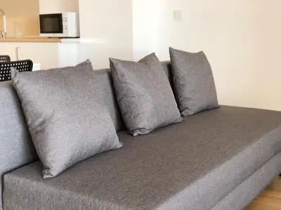 a gray couch with four pillows on it at Global Vacacional, Increíble apartamento con vistas al mar, Canet d'en Berenguer in Canet de Berenguer