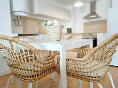 a white table with wicker chairs in a kitchen at Global Vacacional, Apartamento nuevo en la playa de Canet d'en Berenguer in Canet de Berenguer
