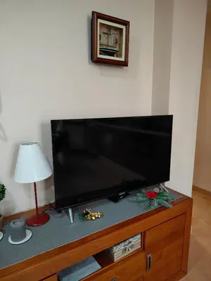 a flat screen tv sitting on top of a wooden entertainment center at Cozy Apartment close to the beach in beatiful area in El Perelló
