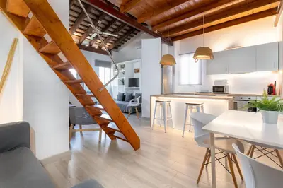 a kitchen and living room with a staircase in a loft at Barón Suites Ruzafa in Valencia