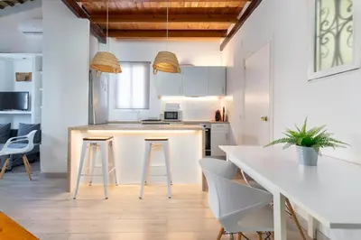 a kitchen with white cabinets and a kitchen island with bar stools at Barón Suites Ruzafa in Valencia