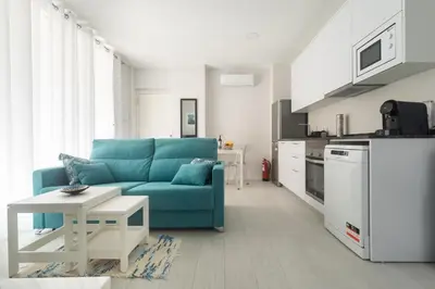 a living room with a blue couch and a kitchen at Reinapart Valencia Beach in Valencia