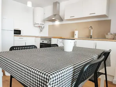 a kitchen with a table with a checkered table cloth at Global Vacacional, Moderno apartamento con terraza y vistas al mar in Canet de Berenguer