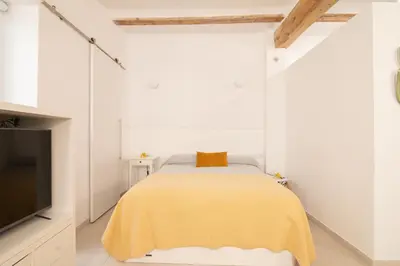 a bedroom with a yellow bed and a tv at Cabanyal old fisherman's house in Valencia