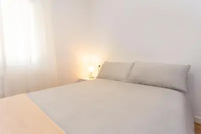a white bed in a white room with a window at Cullera Panoramic Sea Views Apartment in Cullera