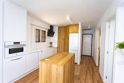 a kitchen with white cabinets and a wooden island at Cullera Panoramic Sea Views Apartment in Cullera