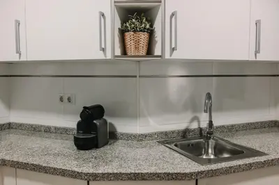 a kitchen counter with a sink and white cabinets at Patacona Beach Apartment in Alboraya