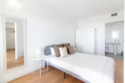a white bedroom with a white bed and a mirror at Global Vacacional, Apartamento con vistas al mar, Canet d'en Berenguer in Canet de Berenguer