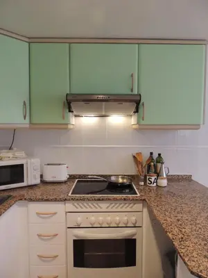 a kitchen with green cabinets and a stove top oven at ACOGEDOR ADOSADO entre mar y montaña in Cullera