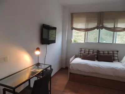 a bedroom with a bed and a desk and a television at ACOGEDOR ADOSADO entre mar y montaña in Cullera