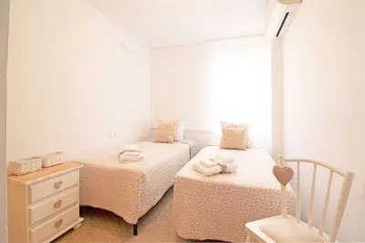 a bedroom with two beds and a dresser and a window at Global Vacacional, Practico apartamento con piscina en Residencial Brezo Canet in Canet de Berenguer