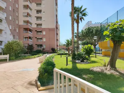 a park with palm trees and a white fence at Global Vacacional, Practico apartamento con piscina en Residencial Brezo Canet in Canet de Berenguer