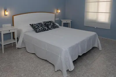 a bedroom with a white bed with a pillow and two tables at CHALET VILLA Los HIPOCAMPOS in Cullera