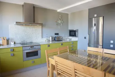 a kitchen with yellow and green cabinets and a dining table at Casa Lucía in Requena