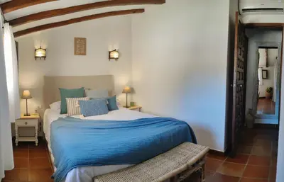 a bedroom with a bed with a blue blanket at MASÍA de SAN JUAN CASA NÚMERO 15 en Castillo con piscina, Aire Acondicionado y terraza privada in Segorbe
