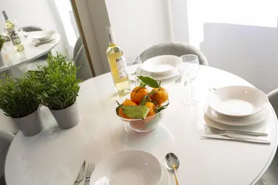 a white table with a bowl of oranges and a bottle of wine at SingularStays Xativa III in Valencia