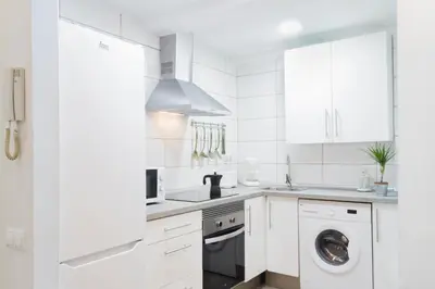 a kitchen with white cabinets and a washer and dryer at Cabanyal Luxury Malvarrosa Beach in Valencia