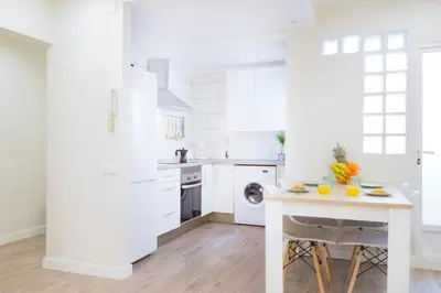 a white kitchen with a table with fruits on it at Cabanyal Luxury Malvarrosa Beach in Valencia