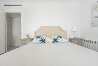 a bedroom with a large white bed with blue pillows at Reinapart Patacona Beach 46 in Valencia