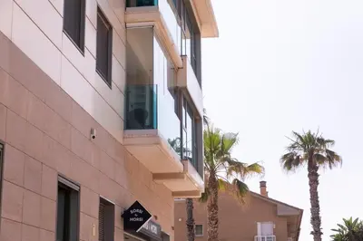 a building with palm trees in front of it at Reinapart Patacona Beach 46 in Valencia