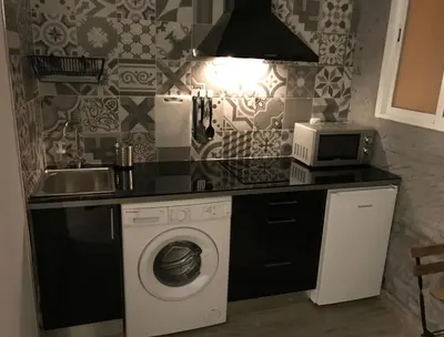 a kitchen with a washing machine and a microwave at Pequeño Alojamiento con Mini Piscina - NO climatizada in Valencia
