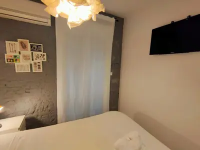 a bedroom with a white bed and a television at Pequeño Alojamiento con Mini Piscina - NO climatizada in Valencia