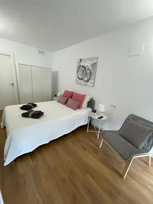 a white bedroom with a large bed and a chair at Canet De Berenguer, Playa Apto con 2 habitaciones in Valencia